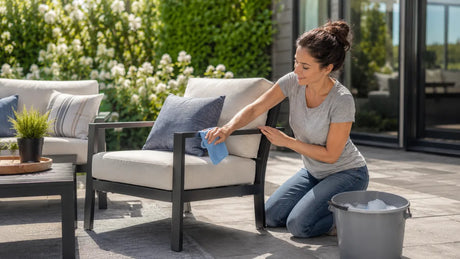 Wiping down an outdoor furniture set with a microfiber cloth on a sunlit patio